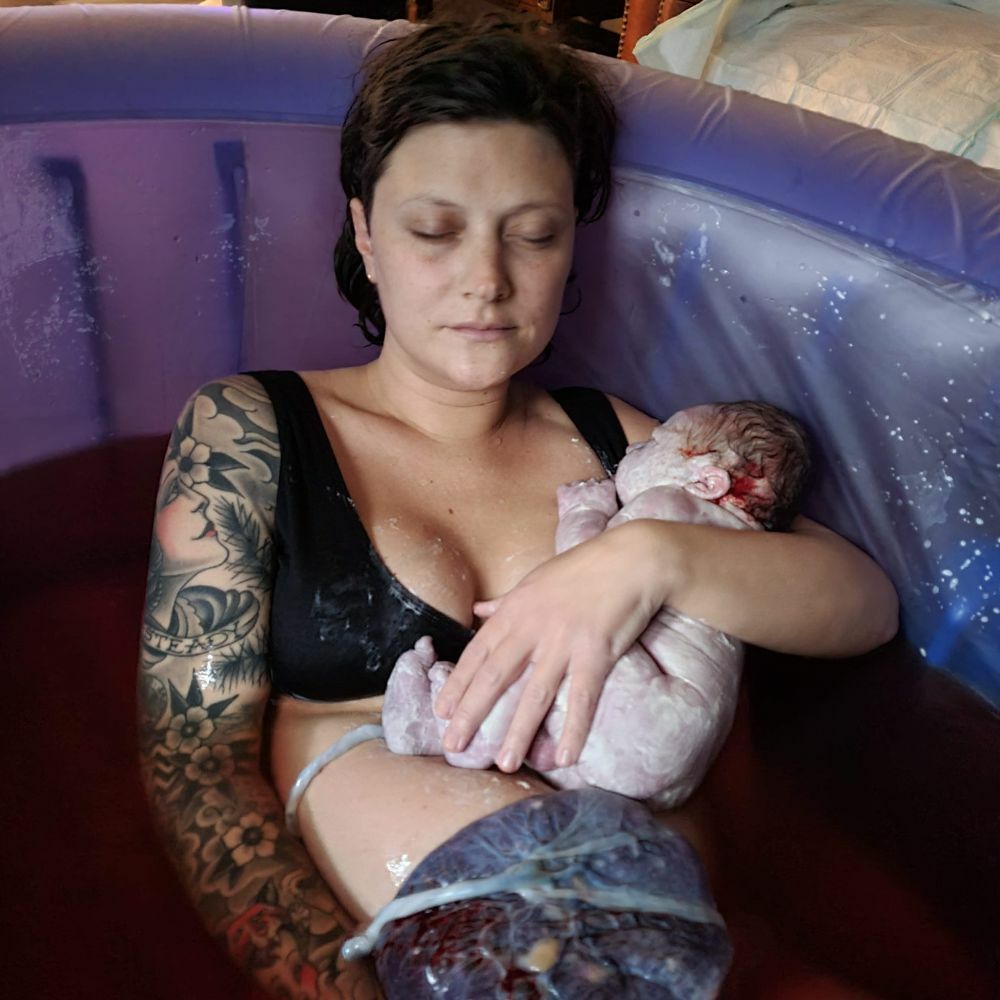 woman holding baby in birthtub